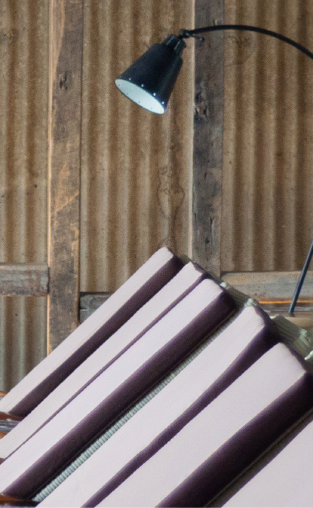 wellness-2 Black desk lamp illuminates stacked purple-and-white corrugated panels against a rustic wooden wall.