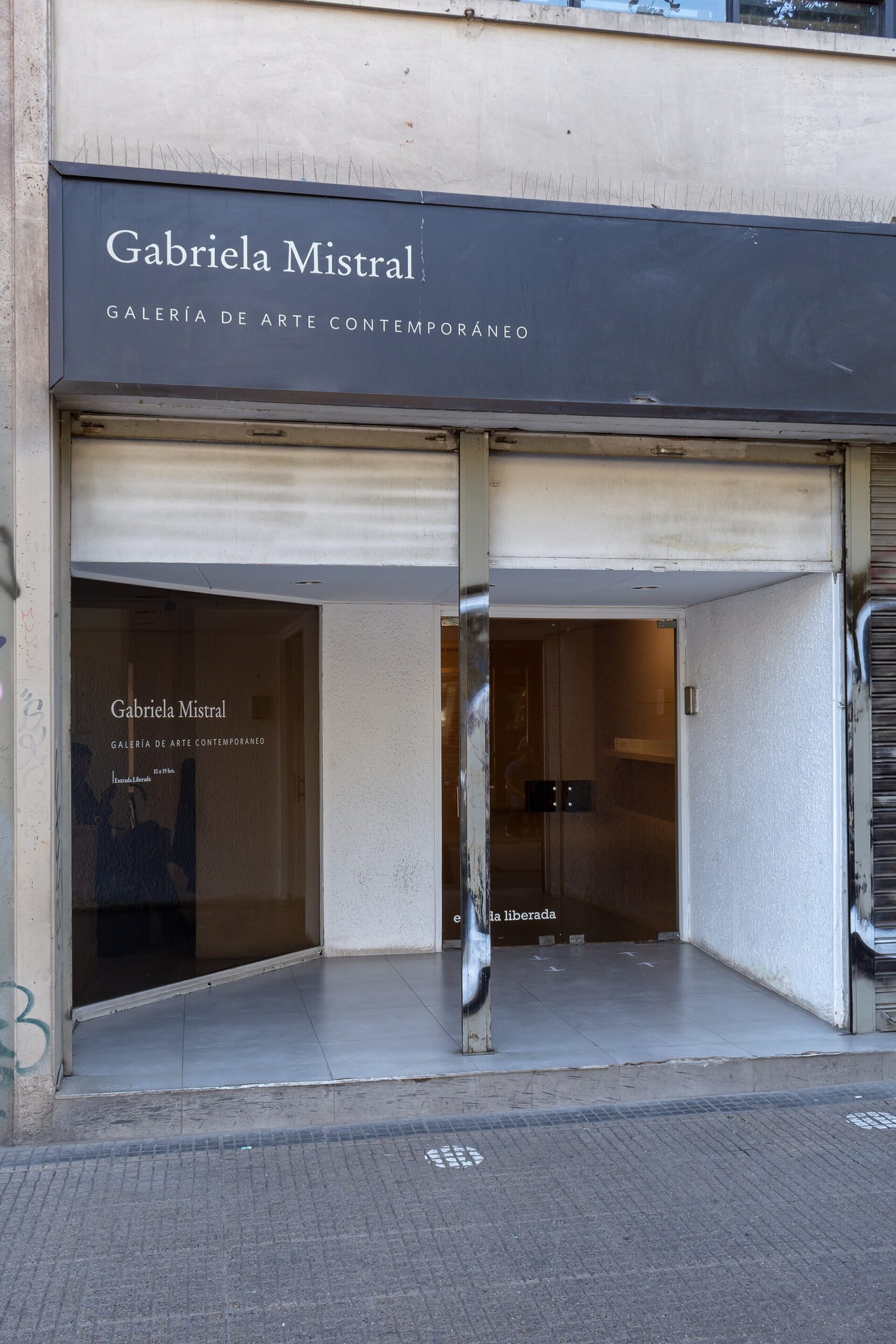 Entrance to Gabriela Mistral Contemporary Art Gallery, with its name displayed on a dark sign above glass doors.