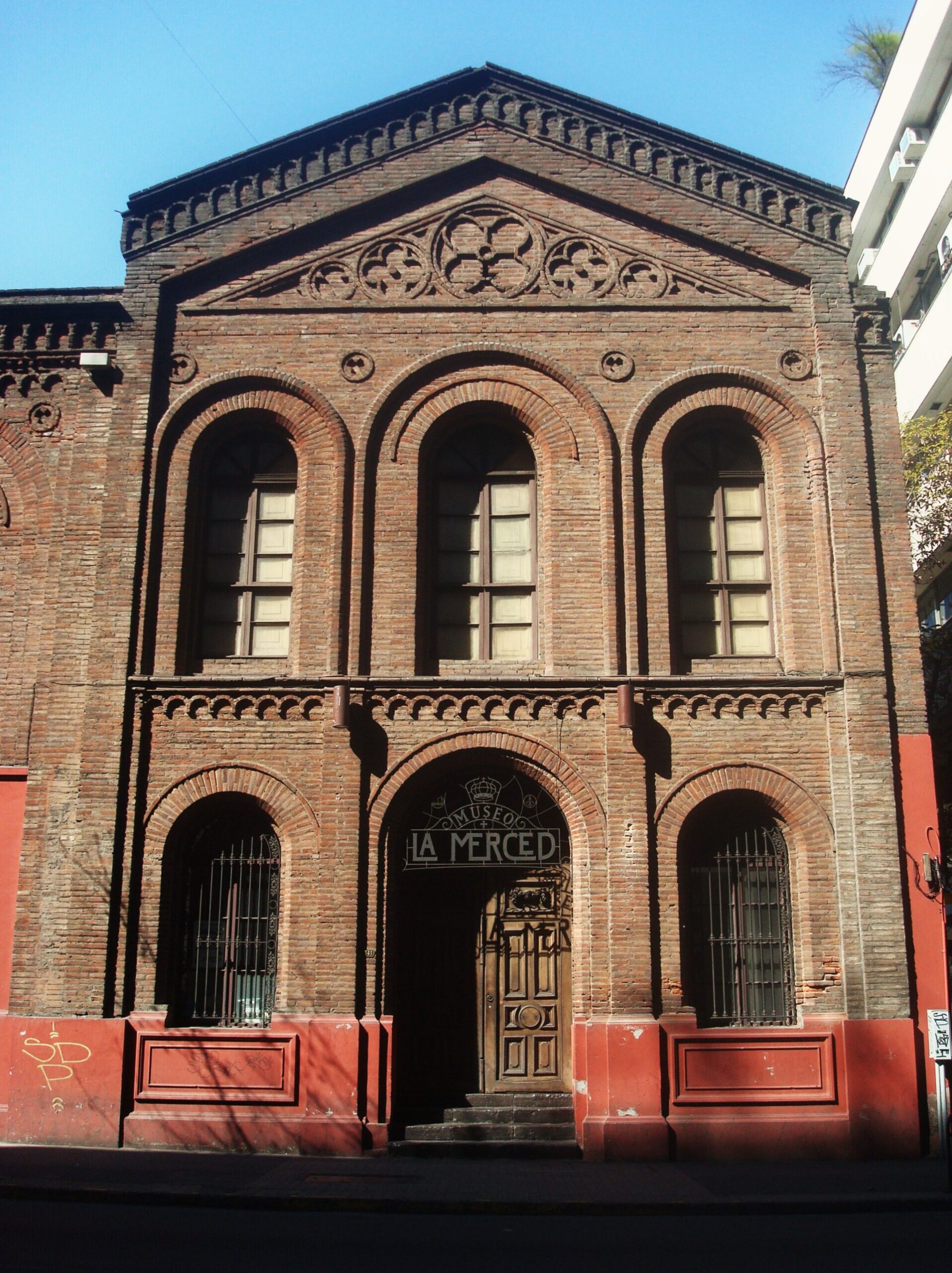 Ornate brick facade of Museo La Merced, featuring arched windows, decorative masonry, and a central wooden entrance.