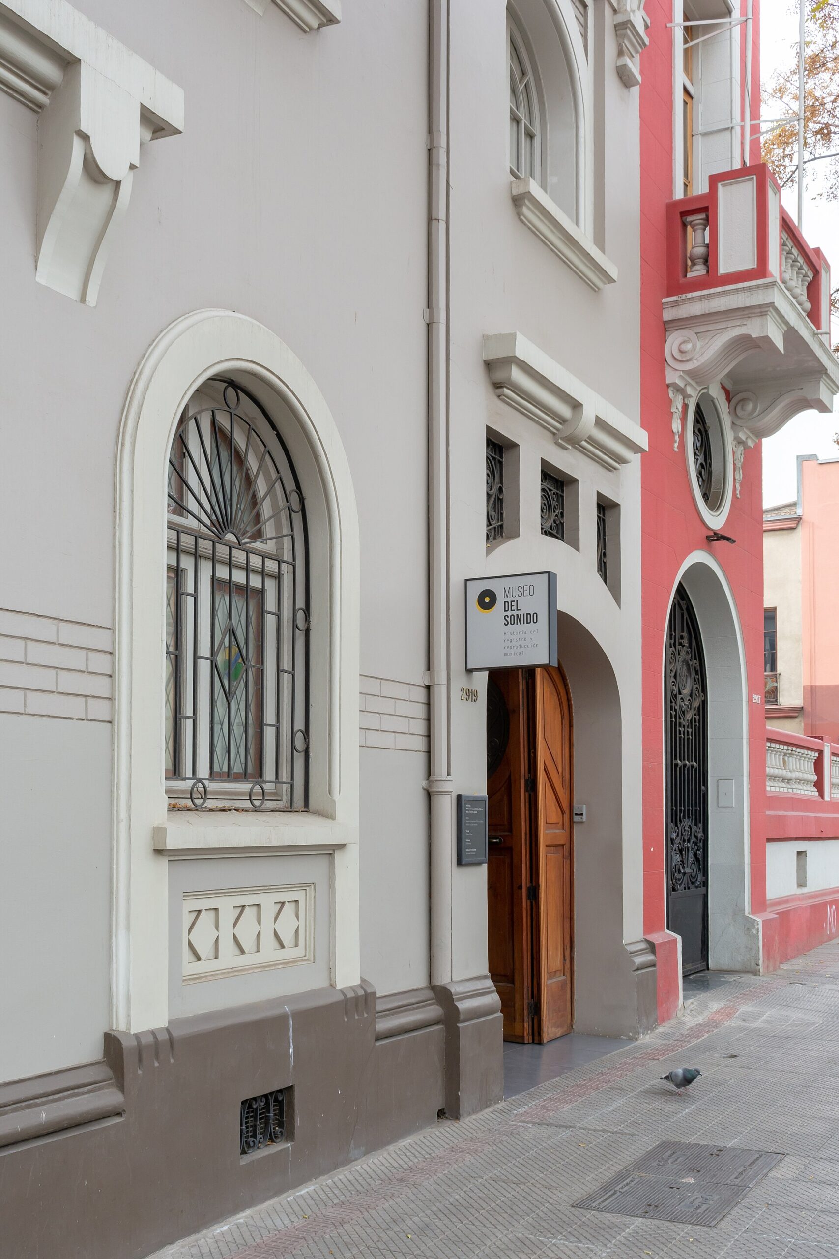 Ornate white and red facade of the Museo del Sonido, with arched iron-grilled windows and a wooden entrance.