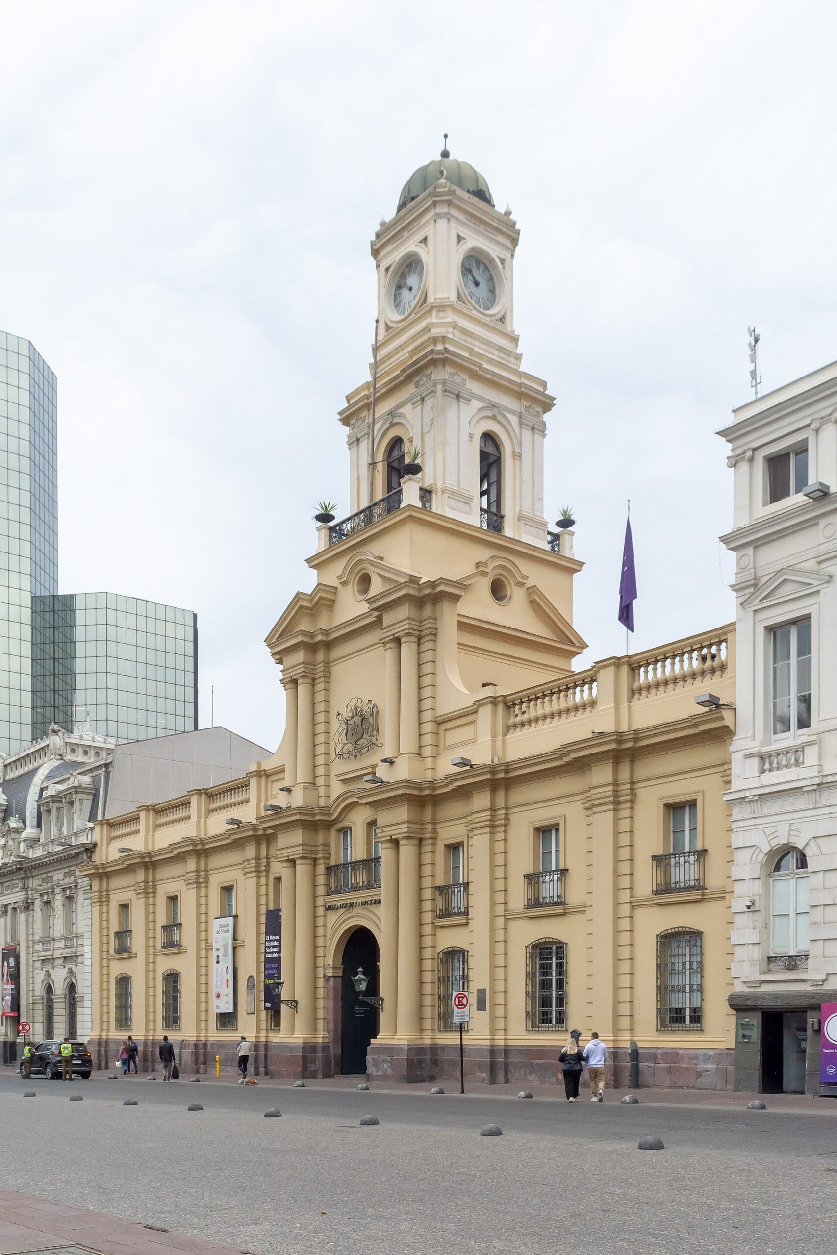 Historic cream-colored building with an ornate clock tower and domed roof on a city street in Santiago, Chile.
