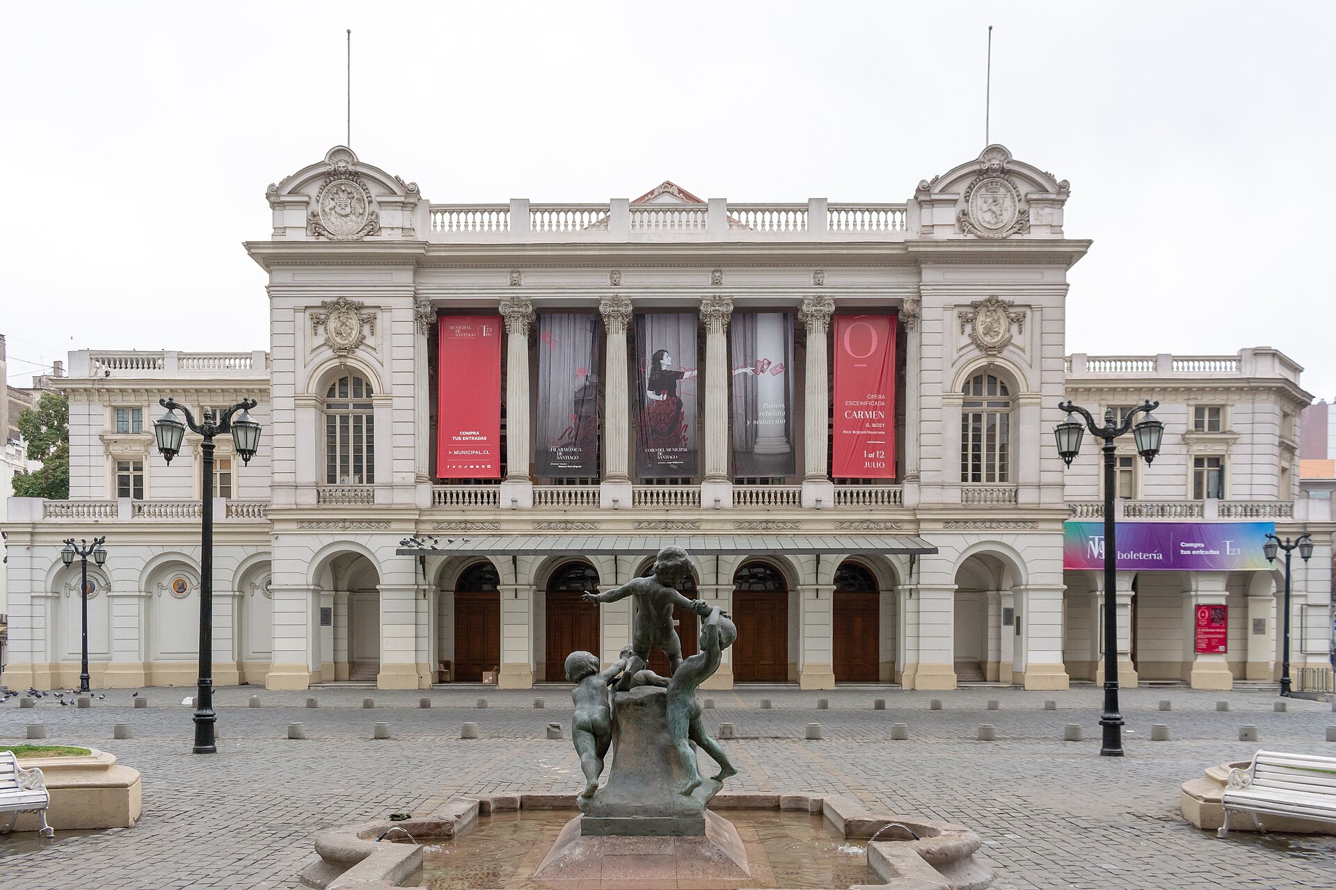 Ornate Santiago Municipal Theater with Carmen opera banners, a bronze fountain sculpture, and lampposts in the plaza.