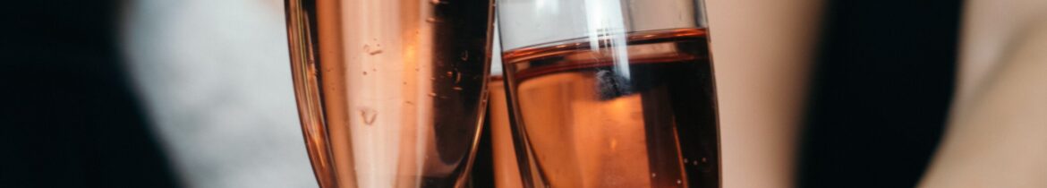 Two people toast with glasses of rosé sparkling wine at a celebration.